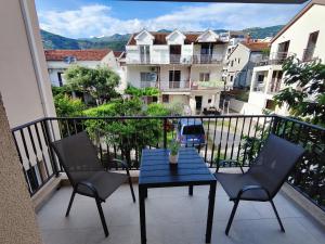 - un balcon avec une table bleue, des chaises et des bâtiments dans l'établissement Bofani Apartments Budva, à Budva