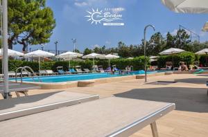 a pool with chairs and umbrellas and people sitting around it at Residence Sunbeam-Padel club in Leporano Marina
