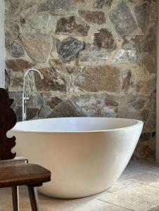uma banheira na casa de banho com uma parede de pedra em Frogs Pond em Red Hill