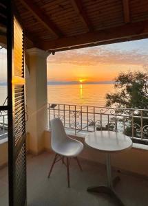 una mesa y una silla en un balcón con puesta de sol en IONIAN MARE, en Agios Ioannis Peristerion