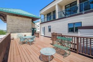 una terraza de madera con mesas y sillas en una casa en Downtown and Waterfront 2BDR Condo in Grand Haven 110 en Grand Haven