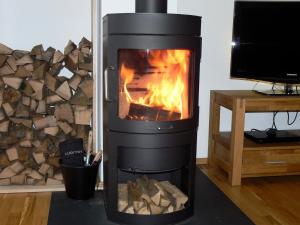 a stove with a fire in it next to a pile of wood at Wetekams Ferienwohnung W5 in Diemelstadt 