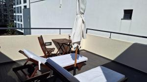 a balcony with chairs and an umbrella and a table at Theo's City House in Funchal