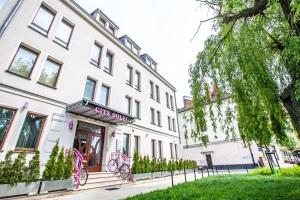 biały budynek z różowymi rowerami zaparkowanymi przed nim w obiekcie City Solei Boutique Hotel w Poznaniu