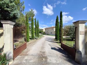a gate to a driveway with trees and a house at Les Grandes Terres - Gîtes & SPA in Mérindol