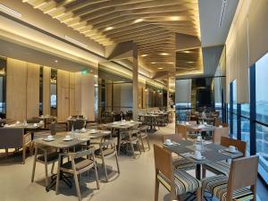 een restaurant met houten tafels, stoelen en ramen bij Swiss-Belinn Simatupang in Jakarta