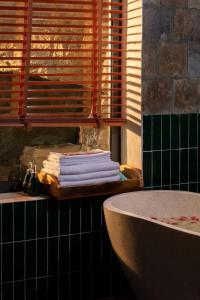 a bathroom with a tub and a stack of towels at Mua Caves Ecolodge (Hang Mua) in Ninh Binh