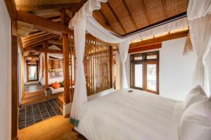 Un dormitorio con una cama blanca en una habitación con techos de madera. en Mua Caves Ecolodge (Hang Mua), en Ninh Binh