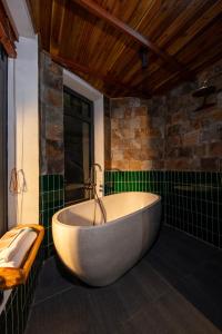 a bath tub in a bathroom with green tiles at Mua Caves Ecolodge (Hang Mua) in Ninh Binh