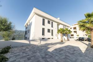 a white building with palm trees in front of it at Villa Velebit - luxury apartment steps away from Adriatic Sea, with private pool and stunning views in Vinjerac