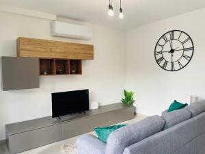 Seabreeze 2 Bedroom Flat في مارساسكالا: غرفة معيشة مع أريكة وساعة على الحائط