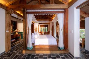 寧平的住宿－姆瓦洞生態酒店（杭姆瓦），卧室配有一张位于房子内的天蓬床