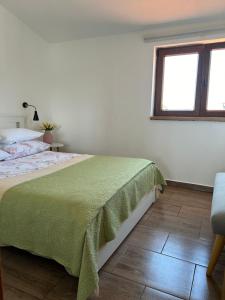 a white bedroom with a bed and a window at VOLMEfamily in Pula