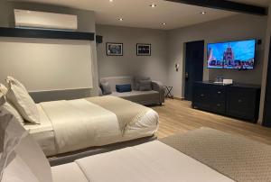 a bedroom with a bed and a couch and a flat screen tv at Hotel Verbena in San Miguel de Allende