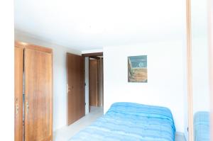 um quarto com uma cama azul e um armário de madeira em la maison jaune em Aosta