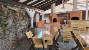 a patio with wooden tables and chairs and a stone wall at PENSIUNEA CASTELANA in Racoşu de Jos