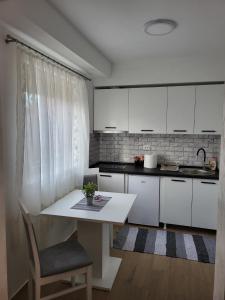 a kitchen with white cabinets and a table at SLEEP & GO in Surčin