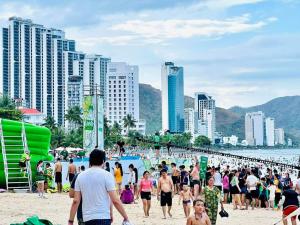 uma multidão de pessoas caminhando em uma praia em Scenia Bay Residence Nha Trang em Nha Trang