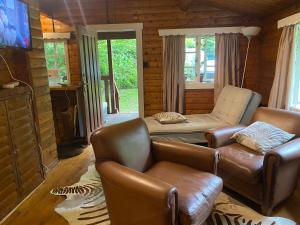 uma sala de estar com sofás de couro e uma televisão em 3bears Log Cabin Whatstandwell Matlock Derbyshire em Crich