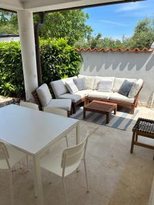 un patio con sofás blancos, mesa y sillas en VOLMEness, en Pula