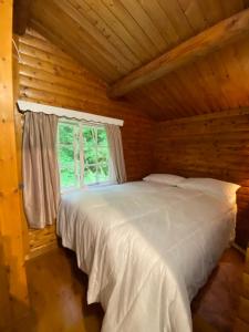1 dormitorio con 1 cama blanca en una cabaña de madera en 3bears Log Cabin Whatstandwell Matlock Derbyshire, en Crich