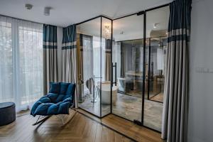 a living room with a blue chair and glass walls at Prawdzic Family Resort & Wellness in Gdańsk