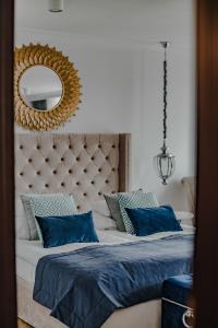 a bedroom with a bed with blue pillows and a mirror at Prawdzic Family Resort & Wellness in Gdańsk