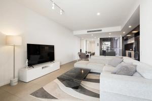 a living room with a white couch and a tv at CASSA OPERA - Spacious 3B Apartment in the Heart Managed by The Cassa in Brisbane