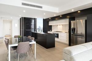 a kitchen and dining room with a table and a refrigerator at CASSA OPERA - Spacious 3B Apartment in the Heart Managed by The Cassa in Brisbane