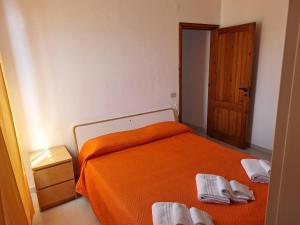 1 dormitorio con cama de color naranja y puerta de madera en Villa 2M a 50 metri dal mare en San Vito lo Capo