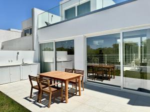 een patio met een houten tafel en stoelen op een balkon bij Feelgood Homestay Sagres in Sagres