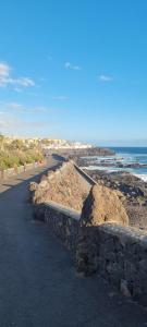 a road with a stone wall next to the ocean at Casita La Ballena Tenerife Sur in Playa de San Juan