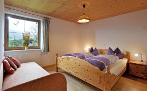 Haus Sonnenschein في تيرسي: غرفة نوم مع سرير خشبي كبير مع وسائد أرجوانية