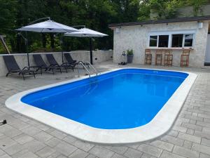 una piscina azul con sillas y sombrilla en 4TREES Holiday House, en Slunj