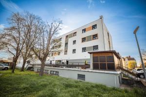 a white building with a tree in front of it at Arion Airport Hotel in Schwechat