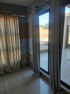 Habitación con ventana grande con cortinas. en Mohau Accommodation, en Elandsfontein