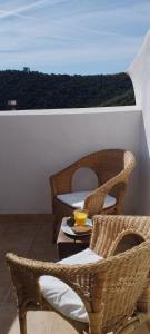 a balcony with wicker chairs and a table with a drink on it at Casa Calma en Sierra de Vicort, Zaragoza in Inogés