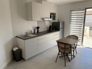 a kitchen with white cabinets and a table and chairs at Studio 2 proche bord de mer 5 mn à pied in Angoulins-sur-Mer