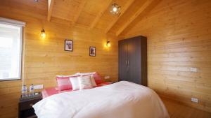 Schlafzimmer mit Holzwänden und einem Bett mit rosa Kissen in der Unterkunft The Great Escape Homestay, Gagar, Nainital in Rāmgarh