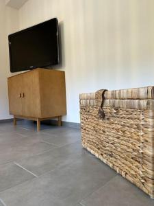 a flat screen tv sitting on a wall next to a wicker cabinet at Appartement Chez Maria in Guebwiller