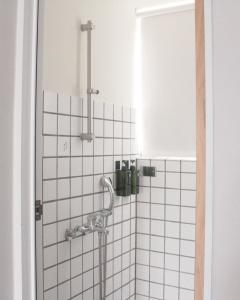 eine Dusche im Bad mit weißen Fliesen in der Unterkunft 落跑吧民宿 in Taitung