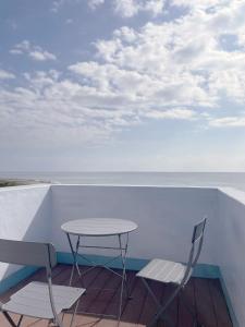 einen Tisch und Stühle auf einem Balkon mit Meerblick in der Unterkunft 落跑吧民宿 in Taitung