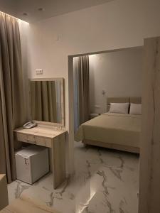 een slaapkamer met een bed, een spiegel en een tafel bij Hotel Lefkes in Paralía Skotínis