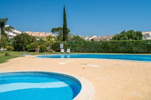 ein großer Swimmingpool mit blauem Wasser in einem Hof in der Unterkunft VILAMOURA Two Bedroom Near Praia Falésia in Quarteira