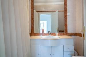 ein Badezimmer mit Waschbecken und Spiegel in der Unterkunft VILAMOURA Two Bedroom Near Praia Falésia in Quarteira + 3 Fotos