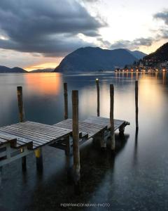 a wooden dock in the water with a sunset at Lake House Valeriana in Pilzone
