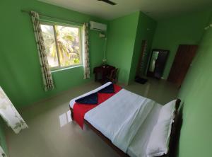 une chambre verte avec un lit avec une couverture rouge et blanche dans l'établissement Chrisander's Resort, à Quepem