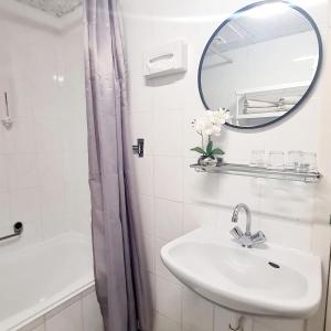 een badkamer met een wastafel, een spiegel en een bad bij Hotel 't Witte Huys Scheveningen in Scheveningen