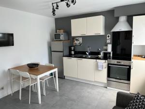 a kitchen with white cabinets and a wooden table at Charmante Maison - Idéalement Située in Ronchin
