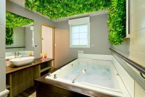 a bathroom with a tub with a sink and a mirror at Domaine Les Saules Hôtel Restaurant Spa in Favières